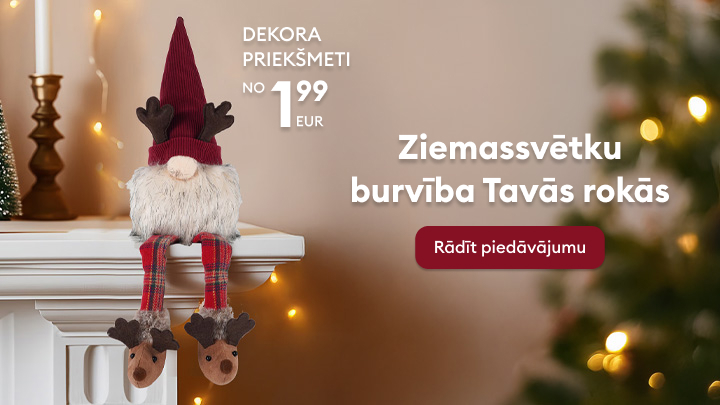 Dekoratīvs rūķis ar Ziemassvētku tematiku sēž uz kamīna malas mājīgā svētku noskaņā. Pieraksts norāda: 
