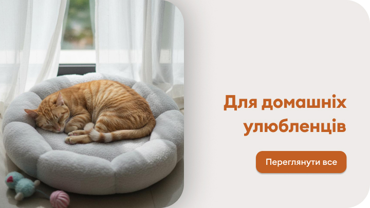 Затишне спальне місце для домашнього улюбленця. Рудий кіт із задоволенням спить на м'якому лежаку біля вікна. Поруч лежать іграшки для тварин. Кнопка закликає переглянути всі товари для домашніх улюбленців.