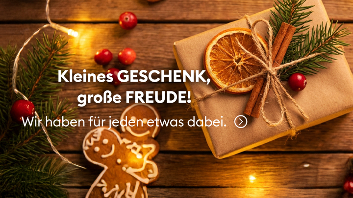Ein verpacktes Geschenk aus Naturmaterialien wie getrocknete Orangenscheiben, Zimtstangen und Tannenzweigen liegt auf einem Holztisch, umgeben von weihnachtlichem Dekor. Darunter steht: „Kleines Geschenk, große Freude! Wir haben für jeden etwas dabei.“ Hinweis auf vielfältige Geschenkideen.