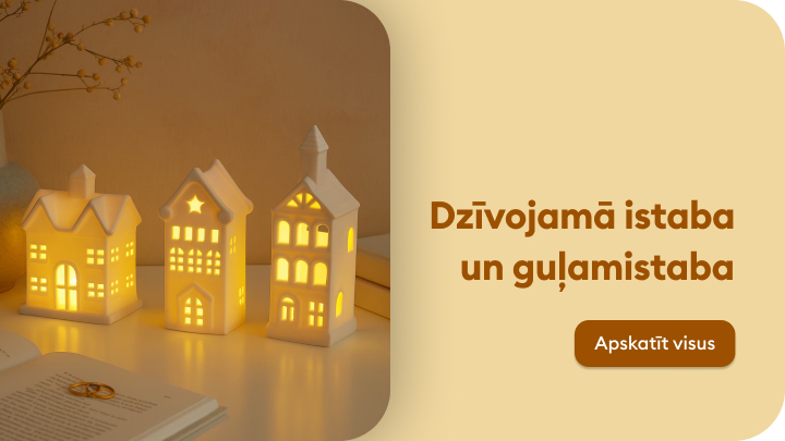 Dekoratīvas keramikas mājiņas ar siltu apgaismojumu novietotas uz galda blakus atvērtai grāmatai un dekoratīvam elementam. Teksts aicina apskatīt mājas dekorācijas, kas piemērotas dzīvojamai istabai un guļamistabai. Poga ar uzrakstu "Apskatīt visus" aicina uz plašāku piedāvājumu.