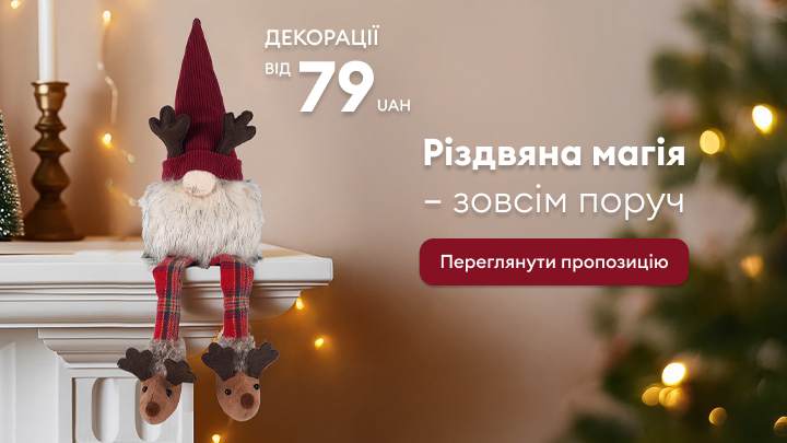 Різдвяний декор: фігурка гномика з червоною шапкою та рогами сидить на краю каміна поруч з святковими прикрасами. Святковий настрій, декорації для вашого дому за ціною від 79 гривень. Текст запрошує переглянути пропозицію на сайті. banner