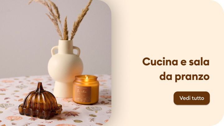 Decorazioni eleganti per cucina e sala da pranzo: vaso in ceramica con grano decorativo, candela profumata e contenitore in vetro ambrato su una tovaglia con motivi autunnali. Scegli accessori raffinati per arricchire il tuo spazio interno. banner