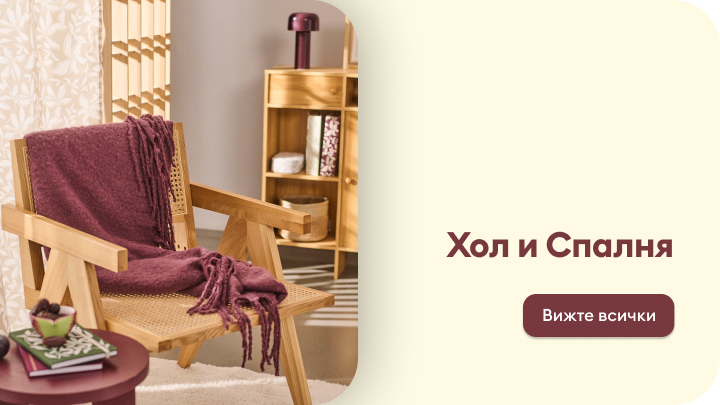 Уютен хол с дървен стол, декориран с меко одеяло, масичка с книга и чаша, и етажерка с рафтове за съхранение. Пространството е подходящо за релакс. Надпис призовава да разгледате всички продукти за обзавеждане на хол и спалня. banner