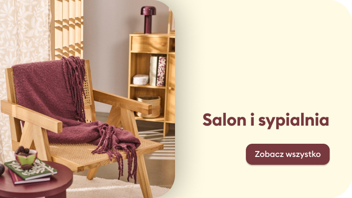 Zdjęcie przedstawia drewniany fotel z bordowym kocem oraz stolik z filiżanką i książkami, w tle regał z dekoracjami. Napis „Salon i sypialnia” zachęca do odkrycia inspiracji związanych z aranżacją wnętrz. Przycisk „Zobacz wszystko” prowadzi do pełnej oferty. banner