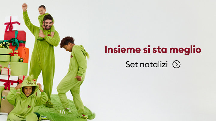 Persone vestite con pigiami verdi posano accanto a una pila di regali natalizi colorati. A destra della scena, il testo: 