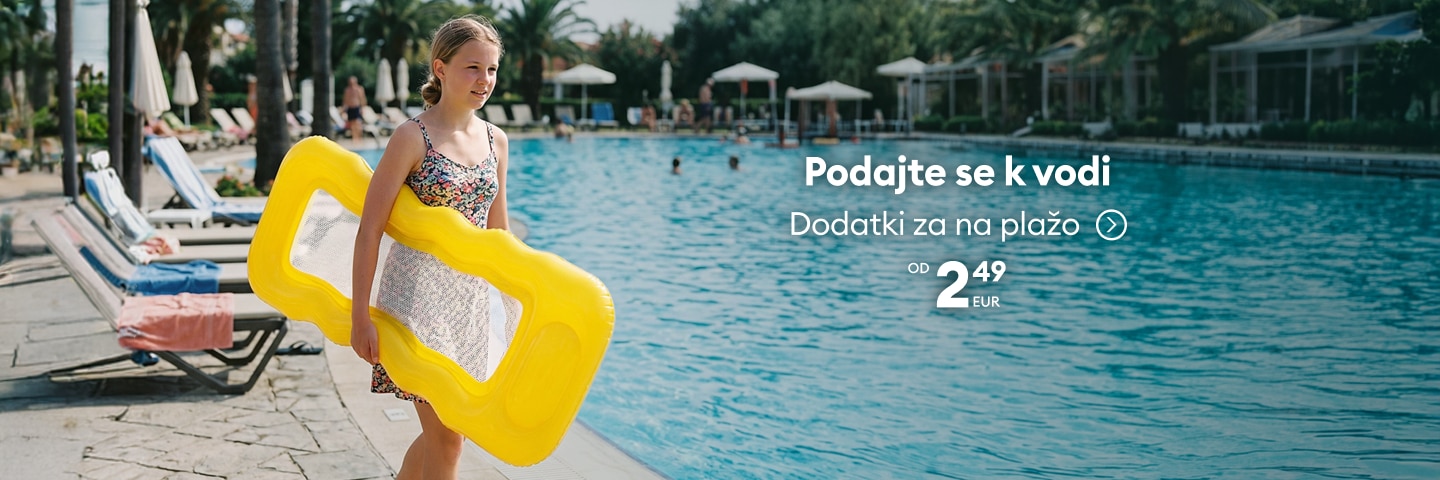 Deklica ob bazenu z napihljivo blazino predstavlja dodatke za plažo in sproščanje ob vodi.