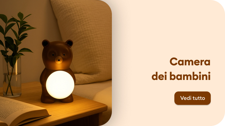 Lampada a forma di orso, posizionata su un comodino accanto a un libro aperto e a una pianta in vaso. La luce diffusa crea un'atmosfera accogliente in una stanza dal design caldo, pensata per i bambini. Un invito a scoprire di più sulla decorazione della camera dei più piccoli. banner